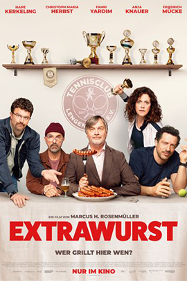 Filmplakat für Extrawurst Vor hellem, neutralem Hintergrund ist eine lange Tafel mit verschiedenen goldenen Pokalen und Schalen aufgebaut, die wie Trophäen aufgereiht sind. Darunter sitzt in der Mitte ein Mann im Anzug mit grauem Haar, der selbstbewusst eine große Wurst präsentiert, während um ihn herum mehrere unterschiedlich gekleidete Erwachsene stehen und sitzen – teils skeptisch, teils ironisch oder amüsiert blickend.