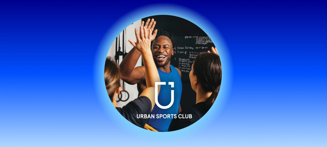  Mehrere Menschen in Sportkleidung geben sich im Fitnessstudio ein High-Five und lachen. 