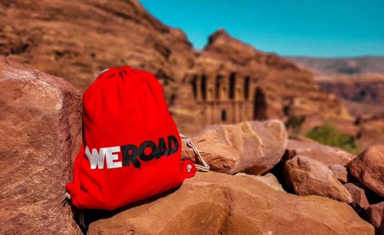 Gewinnspiel WeRoad Roter Rucksack steht auf Felsen in einer Wüstenlandschaft