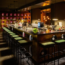  Moderne Bar mit beleuchtetem Tresen und hohen Barhockern. 