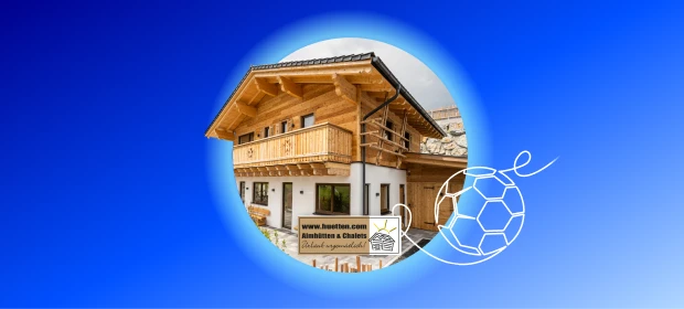 Luftaufnahme einer Ferienanlage mit Holzhäusern in grüner Hügellandschaft. 