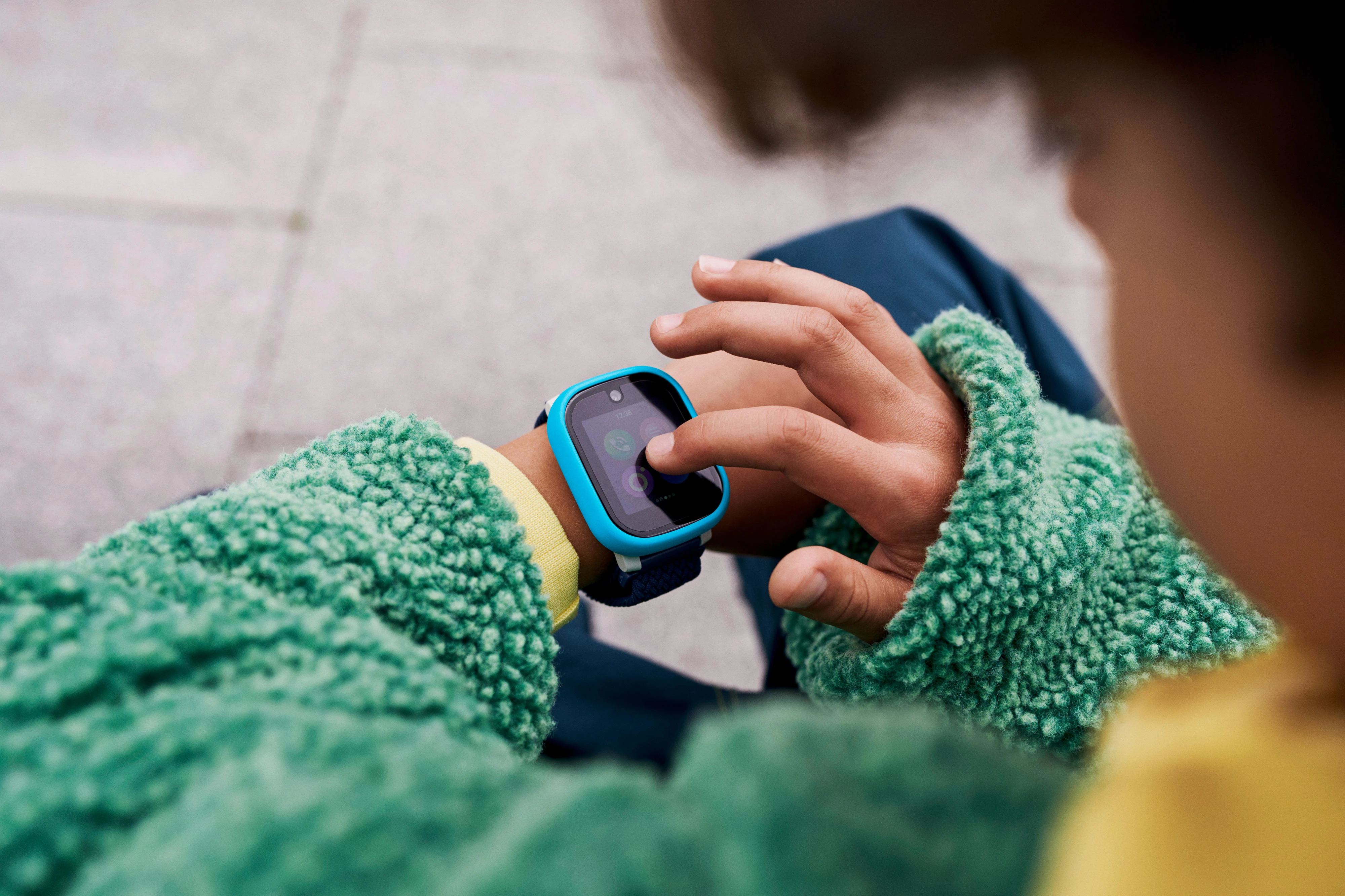 Kind bedient eine Smartwatch am Handgelenk mit einem Finger.
