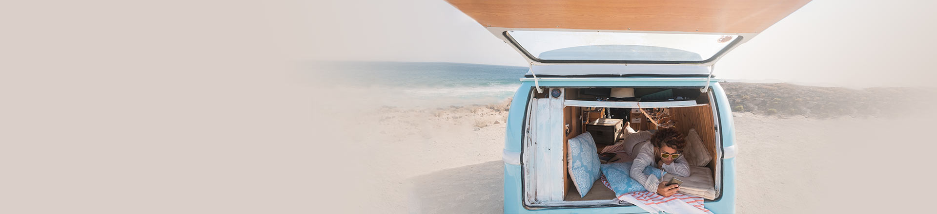 Reise-App: Mann im Auto am Strand