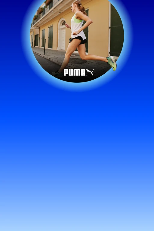  Seitlich laufende Person in weißem Sporttop, schwarzer Shorts und grünen Laufschuhen auf einer Stadtstraße; unten das Puma-Logo. 
