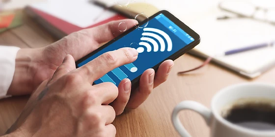 Mensch aktiviert mit seiner Hand die WLAN-Funktion eines Smartphones.