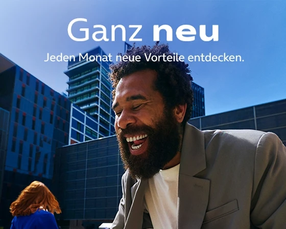 GANZ NEU   Kategoriename: GANZ NEU - Das Kategoriebild zeigt einen lachender Mann mit Bart, der vor einem modernen Bürogebäude steht