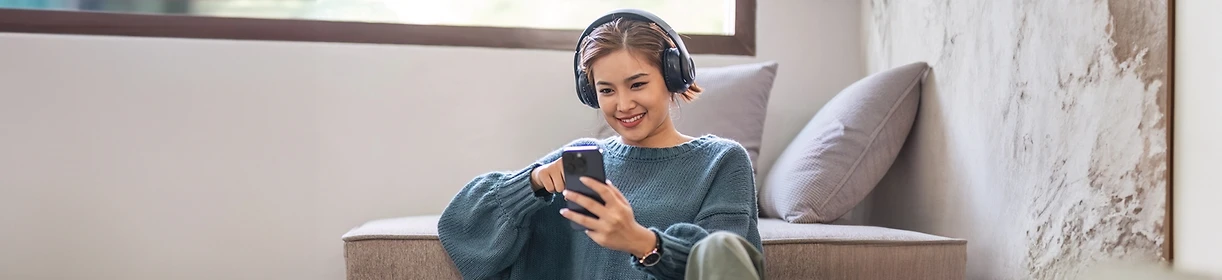 Frau hält Smartphone in der Hand und hört Musik.