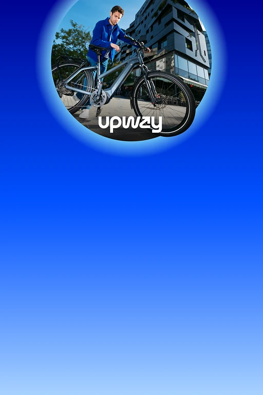  Person steht auf einem gepflasterten Platz und hält ein silbergraues E-Bike. Im Hintergrund moderne mehrstöckige Gebäude mit Glasfassaden und einige Bäume. 